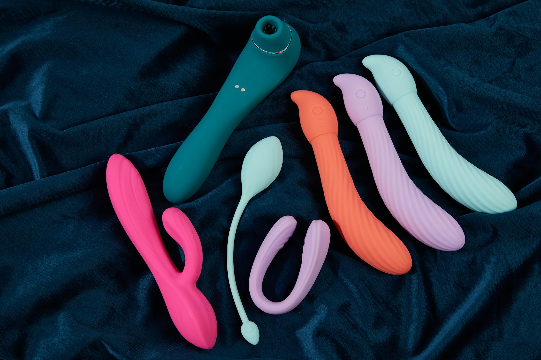 Affichage vibrant de jouets sensuels en silicone sur tissu bleu foncé, mettant en lumière diverses couleurs et formes.