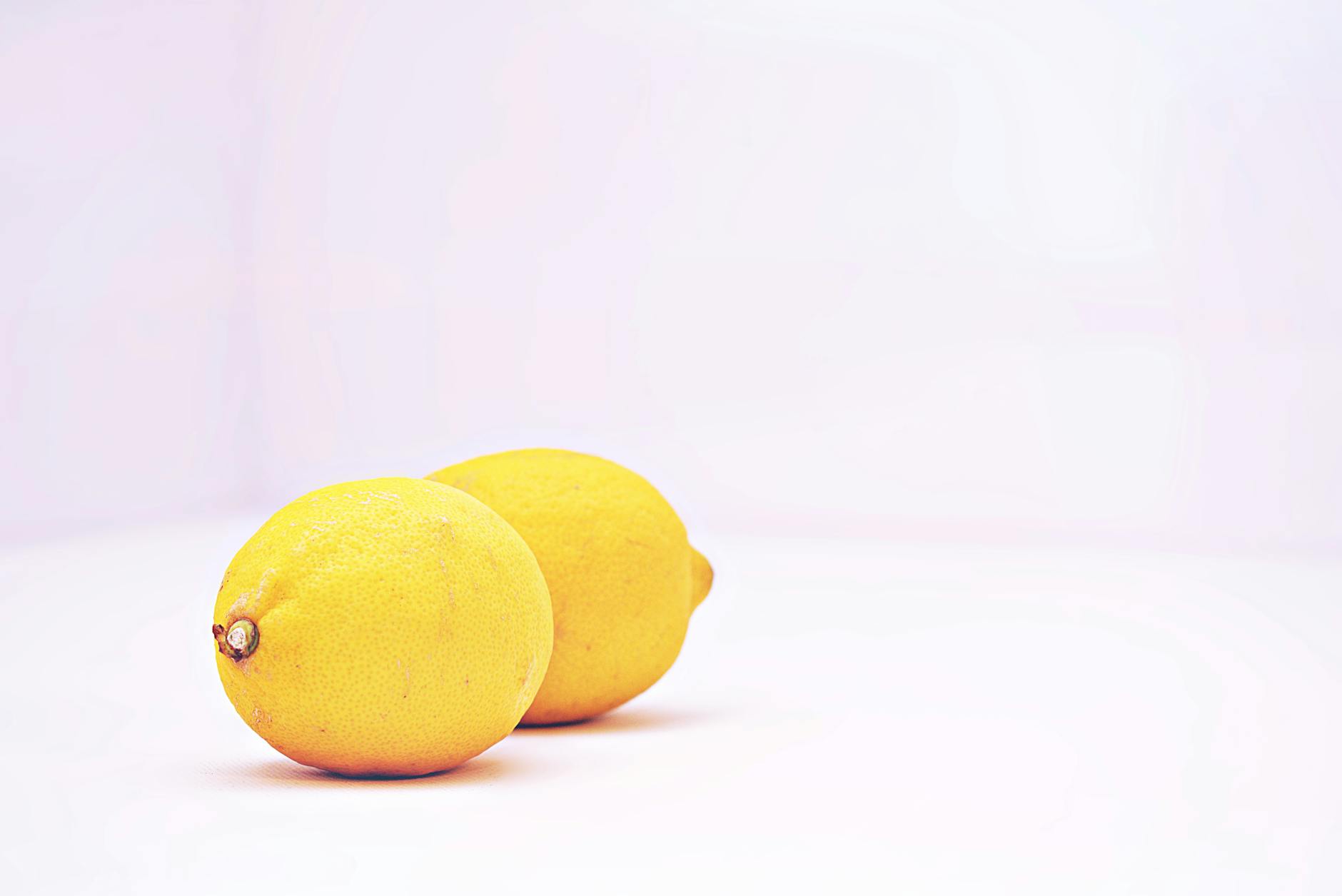 Deux citrons vibrants posés sur un fond blanc minimaliste, symbolisant la fraîcheur et la sensibilité restaurée