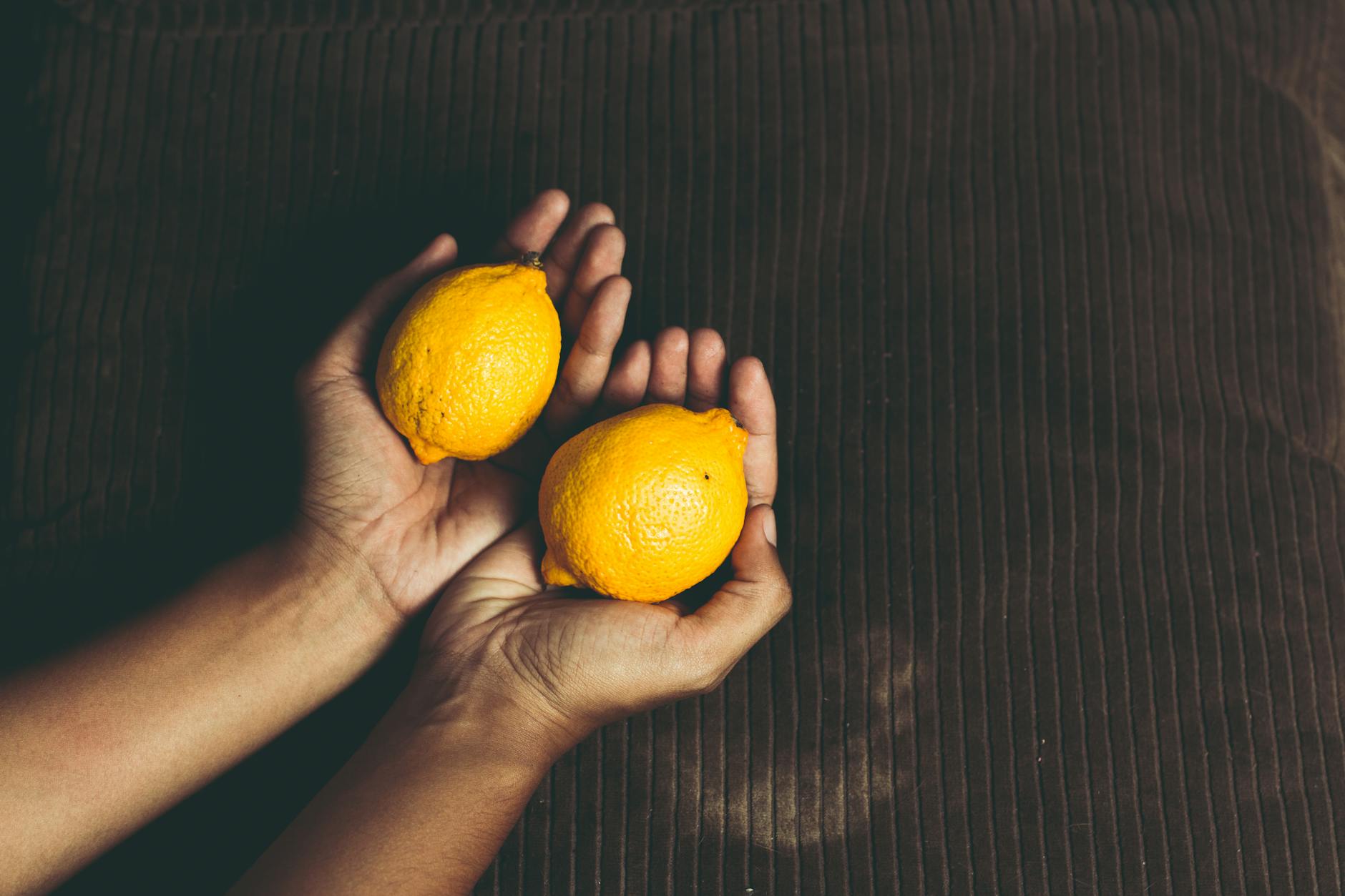 Femme tenant un citron frais à une table, symbolisant la fraîcheur et le renouveau