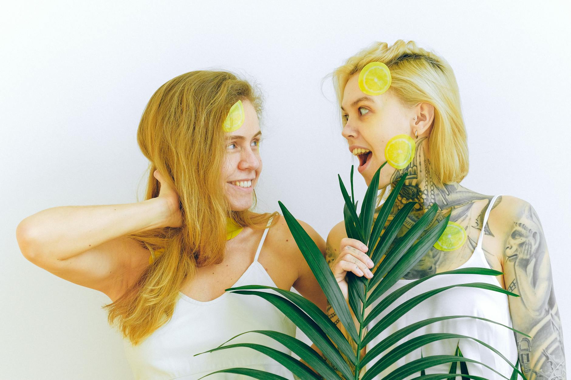Deux femmes souriantes exprimant de la joie avec des tranches de citron et une plante tropicale