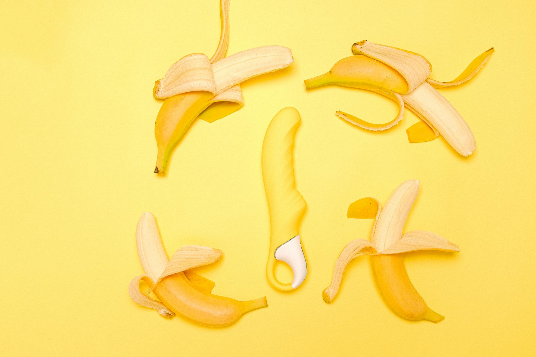 Gelber Silikon-Zitronenvibrator umgeben von geschälten Bananen auf gelbem Hintergrund