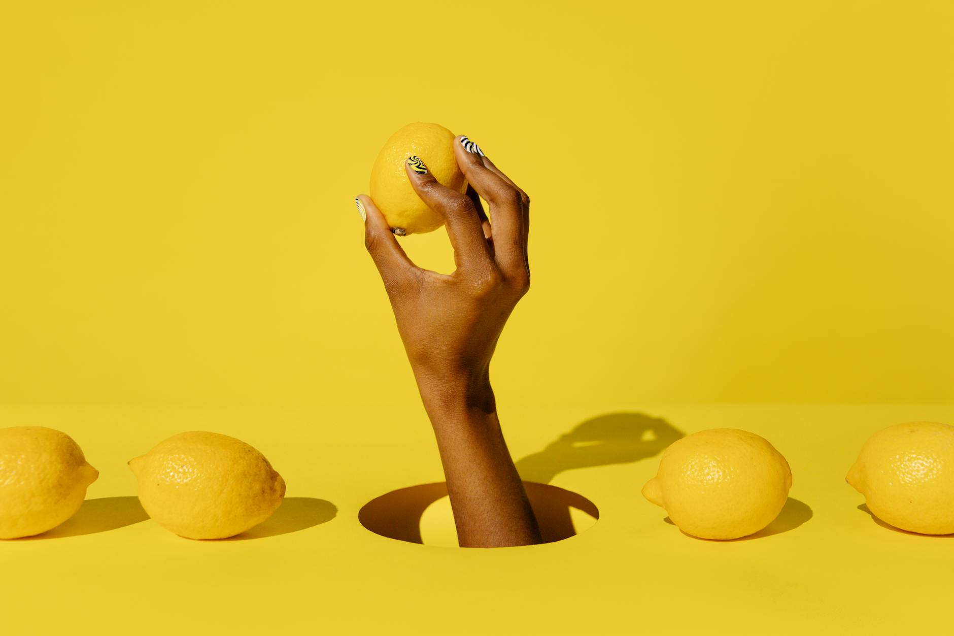 Main tenant un citron frais sur fond jaune vif, évoquant la sensation douce et revigorante