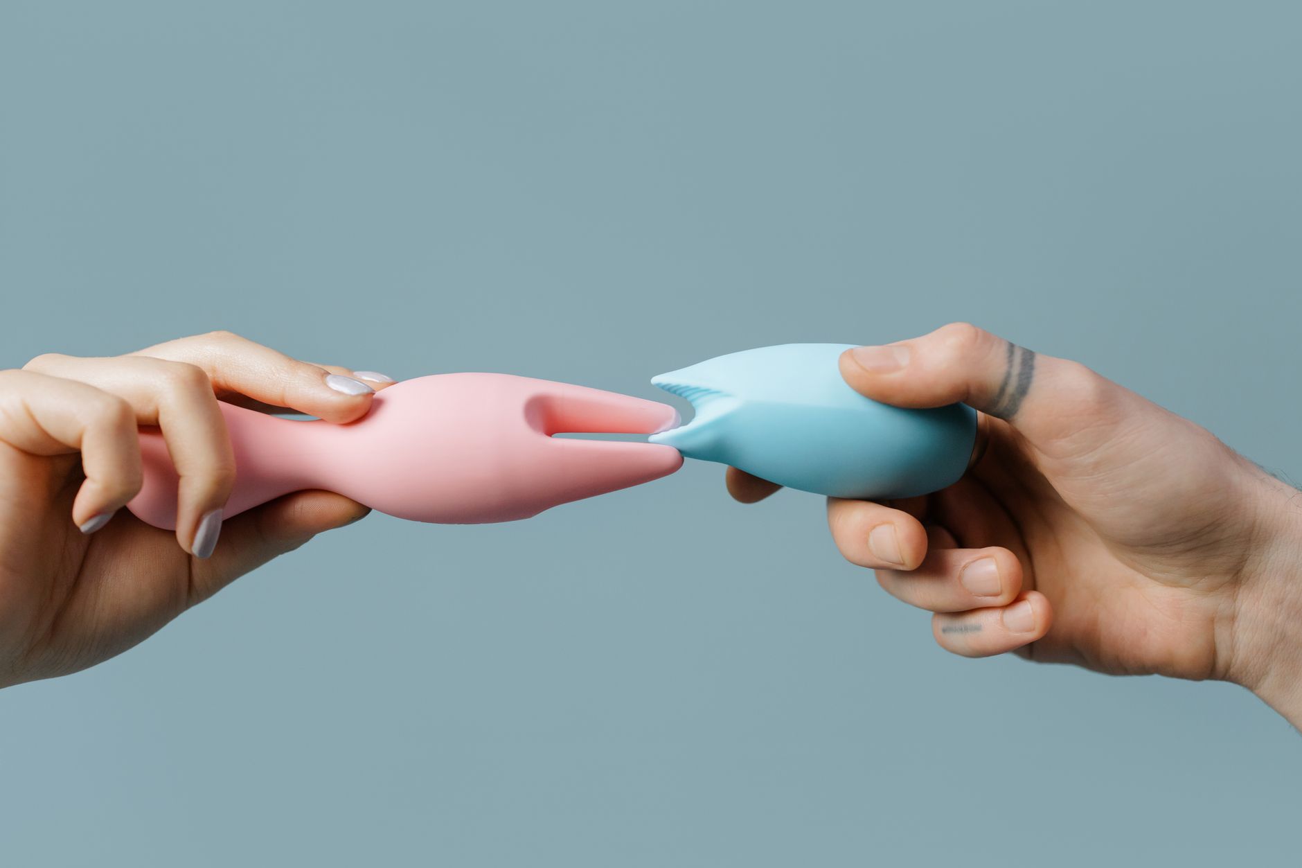 Une main tenant un vibrateur à succion bleu contre un fond violet, symbolisant l'exploration personnelle et l'acceptation de soi