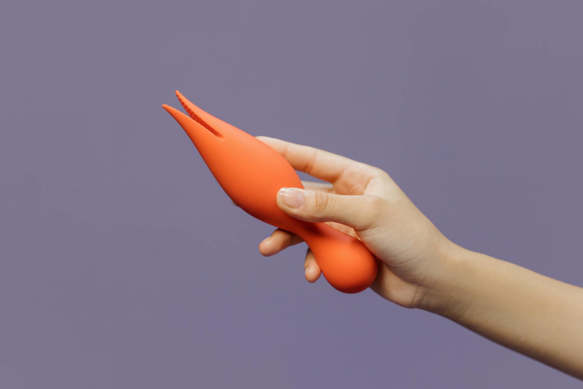 Main tenant un vibrateur citron contre un fond minimaliste violet, mettant en avant la sensualité moderne